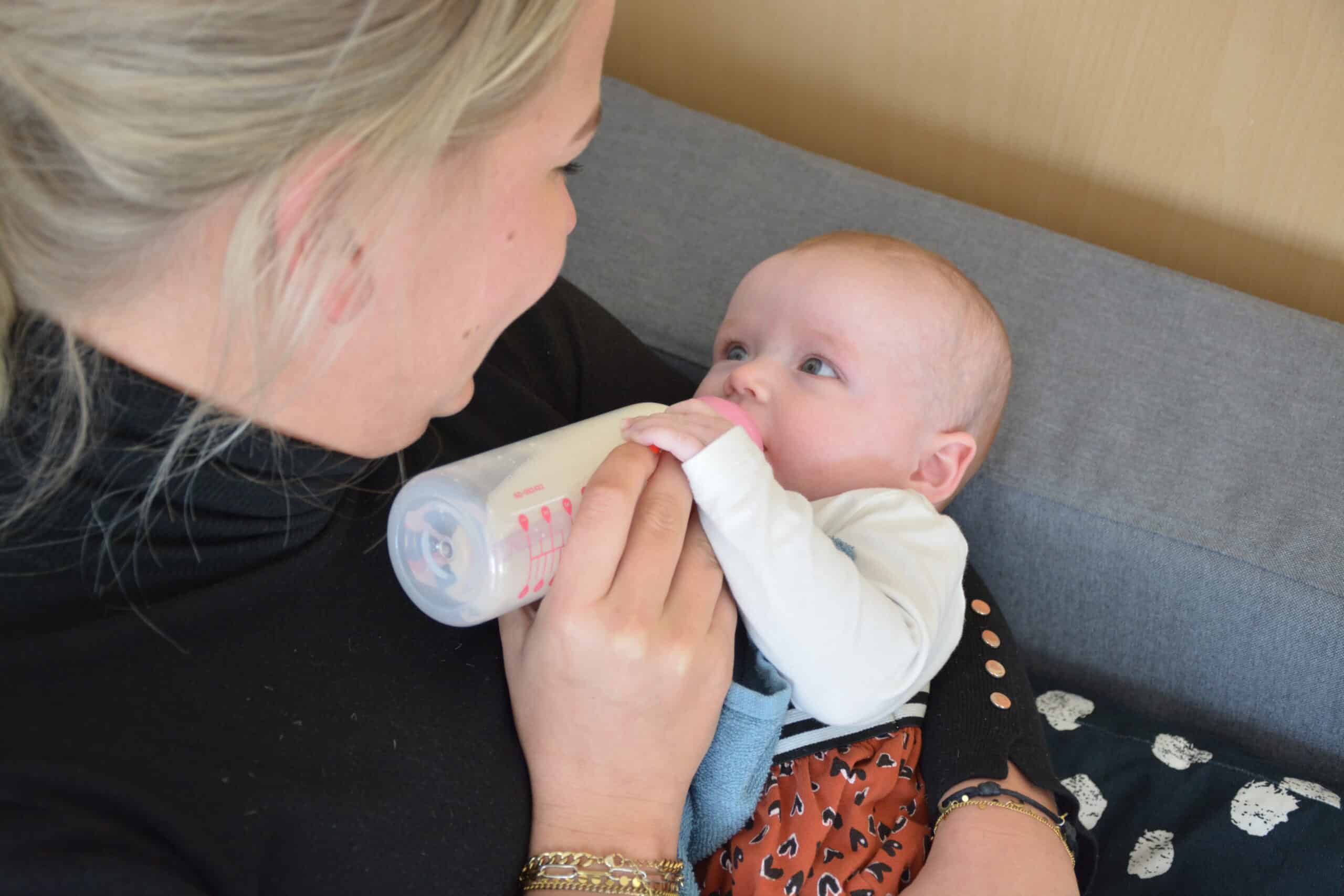 Pedagogisch medewerker geeft baby de fles 