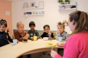 pedagogisch medewerker met kinderen aan tafel